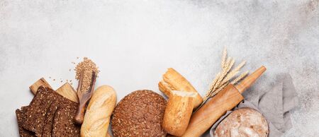Various bread with wheat, flour and cooking utensils on stone table. Top view flat lay with copy...