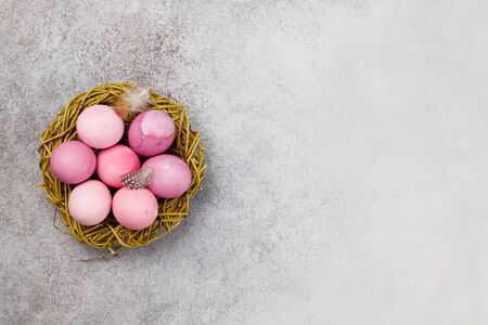 Easter greeting card with pink easter eggs in nest over stone background. Top view flat lay with copy spaceの写真素材