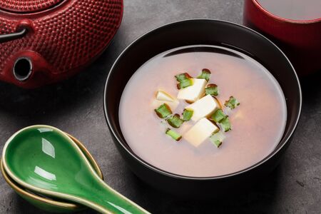 Miso traditional Japanese soup with tofu and spring onion. With green tea in pot and bowlの写真素材