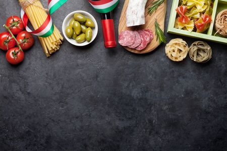 Italian cuisine food ingredients. Pasta, cheese, salami, olives and wine. Top view flat lay on stone table with copy spaceの写真素材