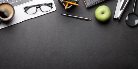 Office desk table with laptop, supplies and coffee. Dark workspace tabletop with copy space. Top...