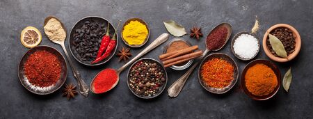 Various spices in bowls and spoons on dark stone table. Indian cuisine. Top view flat lay