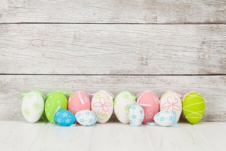 Easter greeting card with colorful easter eggs in front of wooden wall. With space for your...