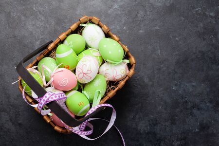 Easter greeting card with colorful easter eggs in basket on stone table. Top view with space for your greetingsの写真素材