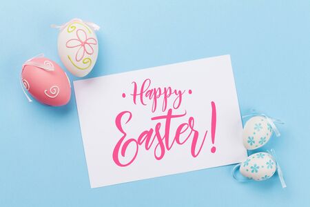 Easter greeting card with colorful easter eggs on blue background. Top view flat lay with space for...