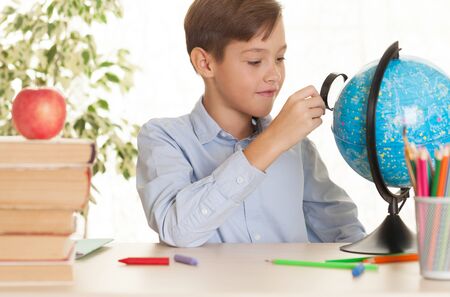 Young schoolboy sitting at the table and doing homework. Elementary education conceptの写真素材