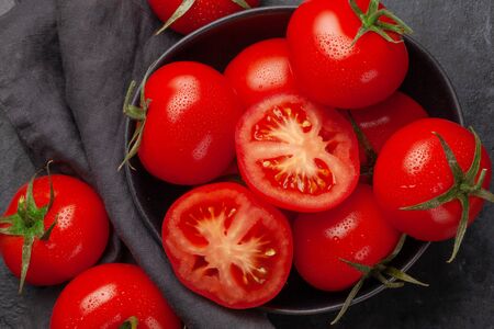 Fresh ripe tomatoes in bowl on stone table. Top viewの写真素材