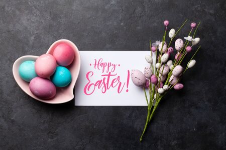 Easter greeting card with colorful easter eggs decor on stone background. Top view flat lay with...