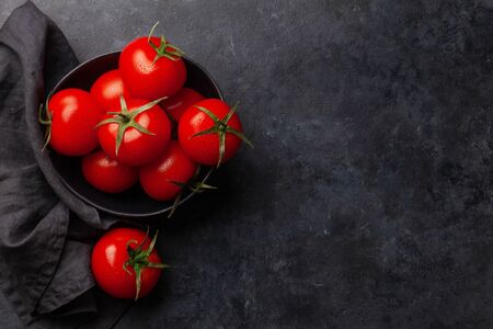 Fresh ripe tomatoes in bowl on stone table. Top view with copy space. Flat layの写真素材