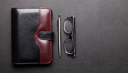 Office desk table with supplies and glasses. Dark workspace tabletop with copy space. Top view flat layの写真素材