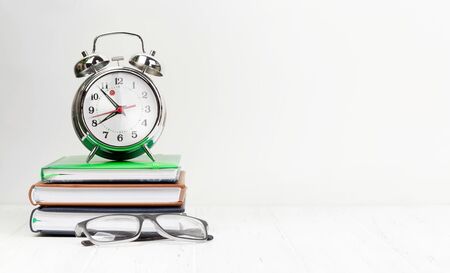 Office workplace desk table with supplies and alarm clock. Morning or deadline concept. With space...