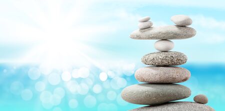Pyramid of sea pebbles on a sunny beach. Life balance and harmony concept