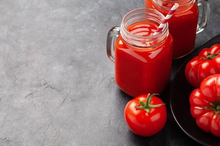 Fresh tomato juice and ripe tomatoes on stone table. With copy spaceの写真素材