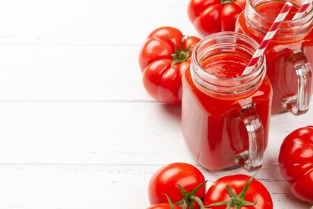 Fresh tomato juice and ripe tomatoes on wooden table. With copy spaceの写真素材