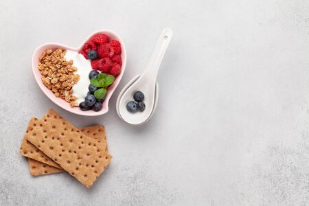 Healthy breakfast with homemade granola with yogurt and fresh berries on stone background. Top view with copy spaceの写真素材