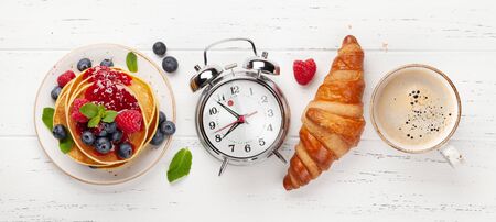 Delicious homemade pancakes with summer berries and jam, croissants and coffee for breakfast. Top...