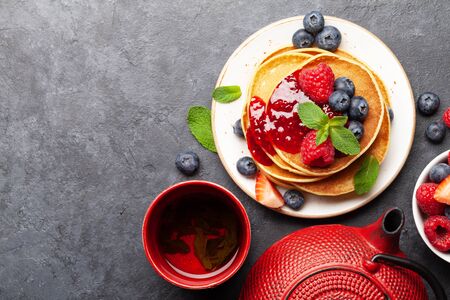 Delicious homemade pancakes with summer berries and tea for breakfast. Top view with copy spaceの写真素材