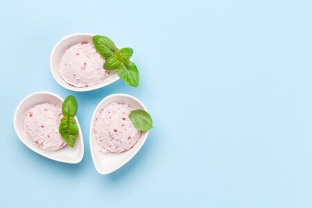 Raspberry ice cream scoops in bowls on blue background. Top view with copy space. Flat lay