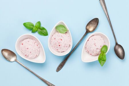 Raspberry ice cream scoops in bowls on blue background. Top view with copy space. Flat lay