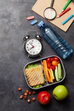 School lunch box and education stationery on stone table. Top view with copy space. Flat layの写真素材