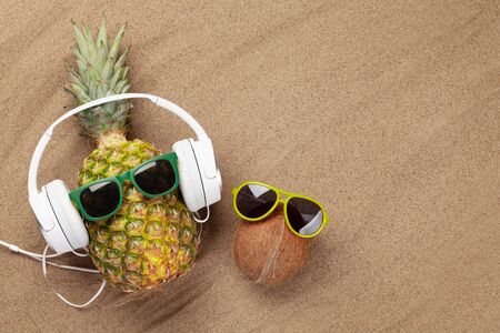 Ripe pineapple and coconut with sunglasses over sand background with copy space. Travel and vacation concept. Top view flat layの写真素材