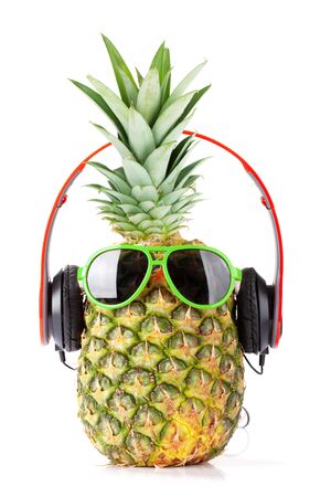 Ripe pineapple with sunglasses and headphones isolated on white background. Travel and vacation conceptの写真素材