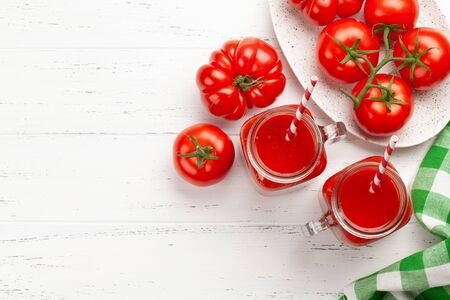 Fresh tomato juice and ripe tomatoes on wooden table. Top view with copy spaceの写真素材