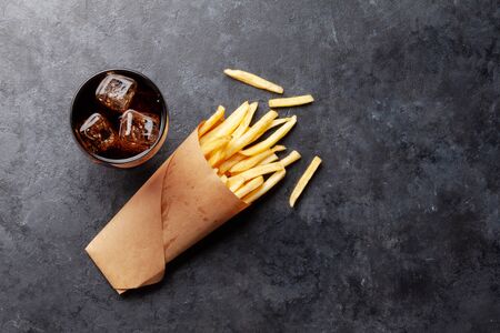 Glass of cola drink with ice and potato fries chips. Fast food take away. Top view with copy spaceの写真素材