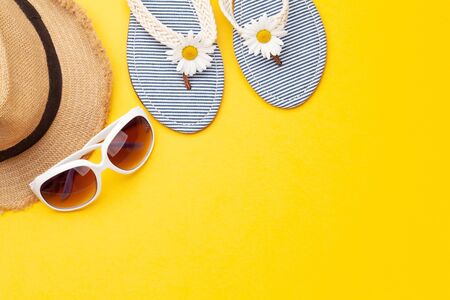 Summer vacation items and accessories. Flip flops, sunglasses and sun hat on yellow background. Top view flat lay with copy spaceの写真素材