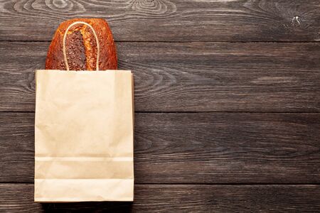 Homemade organic bread with seeds in paper bag on wooden table. Top view flat lay with copy spaceの写真素材