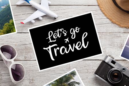 Travel concept with vacation photos, airplane toy, camera and sunglasses on wooden table. Top view flat lay with copy spaceの写真素材