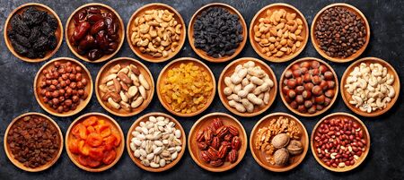 Various dried fruits and nuts bowls on a stone table. Top view flat layの写真素材
