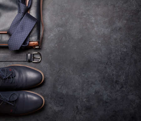 Set of men's classic clothes as tie, belt, shoes and bag on stone background with copy space. Top view flat layの写真素材