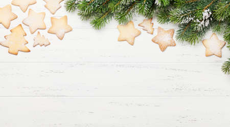 Christmas gingerbread cookies and xmas fir tree branch over wooden backdrop. Top view with space for your greetingsの写真素材