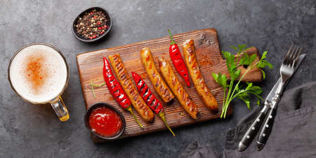 Grilled sausages with spices and herbs and glass of beer. Top view flat layの写真素材