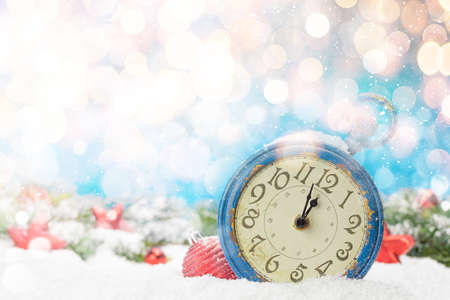 Christmas greeting card with alarm clock and decor in snow over blurred bokeh background and copy space for xmas greetingsの写真素材