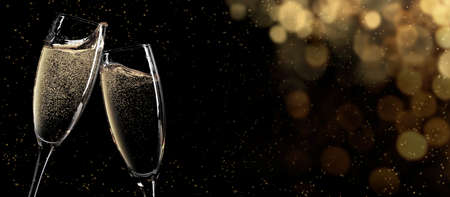 Christmas and New Year wide bokeh backdrop. Xmas greeting card template background with champagne glasses and copy spaceの写真素材