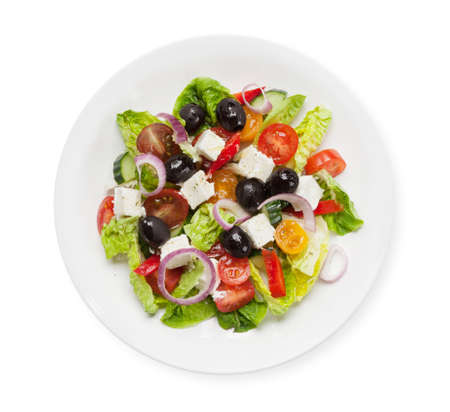 Greek salad with cucumber, tomato, pepper, lettuce, onion, feta cheese and olives, dressed with olive oil. Top view flat lay isolated on whiteの写真素材
