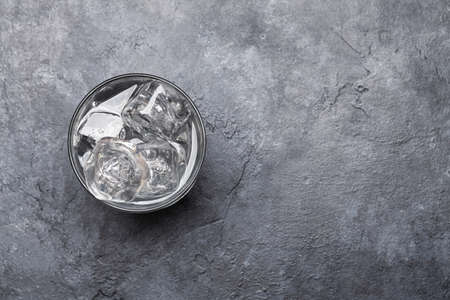 Glass of water with ice cubes on stone table. Top view flat lay with copy spaceの写真素材
