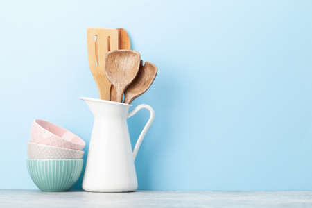 Kitchen utensils and dishes in front of blue background with copy space