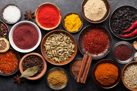 Various spices in bowls on dark stone table. Indian cuisine. Top view flat lay