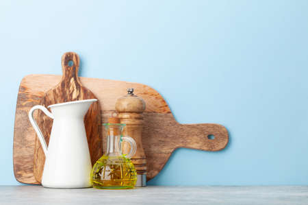 Kitchen utensils and dishes in front of blue background with copy space