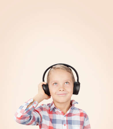 Young boy listening to music with headphones. Over color background with copy space