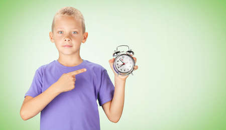 School boy showing alarm clock. Over color backgroundの写真素材