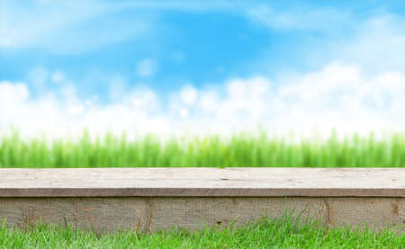 Empty wooden table with outdoor garden grass bokeh and sunny sky. Template backdrop for display your productの写真素材