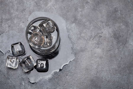 Glass of water with ice cubes on stone table. Top view flat lay with copy spaceの写真素材