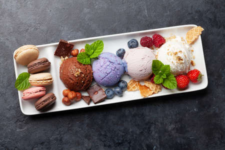 Berry, vanilla and chocolate ice cream scoopes and macaroon sweets. Top view flat lay