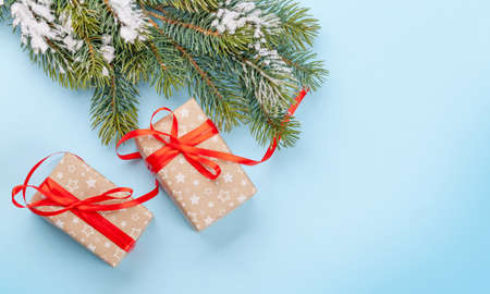 Christmas gift boxes and fir tree over blue background with space for your greetings. Top view flat...