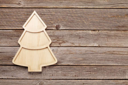 Christmas greeting card with fir tree shaped board on wooden table. Top view flat lay with copy space for your xmas greetingsの写真素材