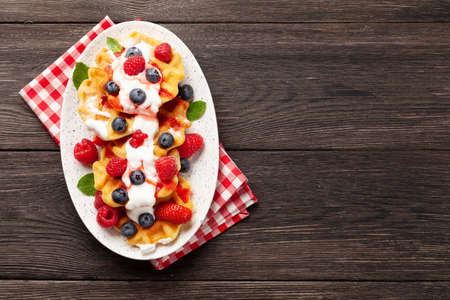 Delicious belgian waffles with ice cream and summer berries. Top view with copy spaceの写真素材